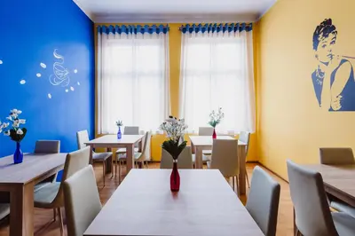 a restaurant with tables and chairs and a painting on the wall at Hostel Tara in Kraków