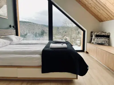 a bedroom with a bed and a large window at Drwalówka - Domek 