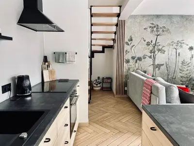 a kitchen with a black counter top and a living room at Drwalówka - Domek 