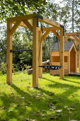 a swing in a wooden structure in the grass at Drwalówka - Domek 