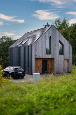 a black car parked in front of a wooden building at Drwalówka - Domek 
