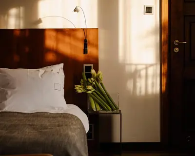 a bed with a white pillow and flowers on a table at Hotel Copernicus in Kraków