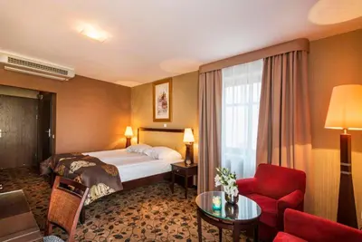 a hotel room with a bed and a red chair at Great Polonia Kraków Kazimierz in Kraków