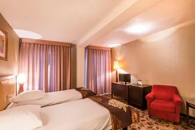 a hotel room with two beds and a red chair at Great Polonia Kraków Kazimierz in Kraków