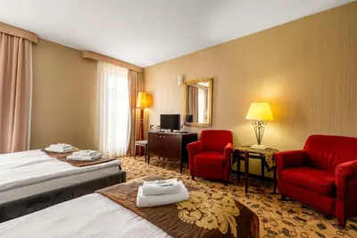 a hotel room with a bed and two red chairs at Great Polonia Kraków Kazimierz in Kraków