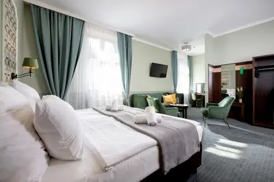 a hotel room with a bed and a desk and chairs at Amber Boutique Hotels - Hotel Amber in Kraków