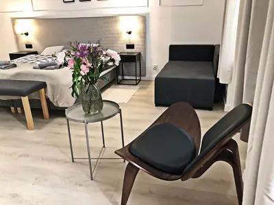 a bedroom with a bed and a chair and a table with flowers at Anny 5 Apartamenty in Kraków