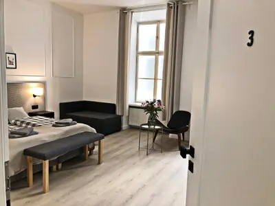 a bedroom with a bed and a chair and a window at Anny 5 Apartamenty in Kraków