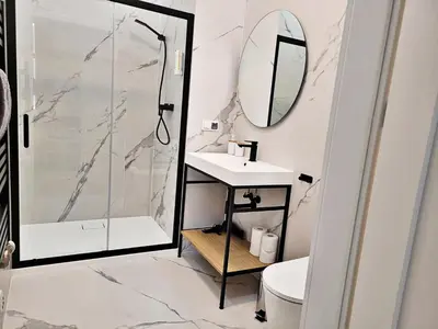 a bathroom with a shower and a sink and a mirror at Anny 5 Apartamenty in Kraków