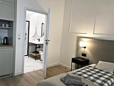 a bedroom with a bed and a bathroom with a sink at Anny 5 Apartamenty in Kraków