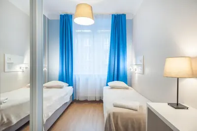 a room with two beds and a window with blue curtains at Premium Hostel in Kraków