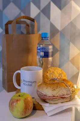 a table with a cup of coffee and a sandwich and an apple at Premium Hostel in Kraków