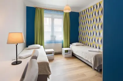 two beds in a room with blue walls and a window at Premium Hostel in Kraków