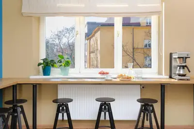 a kitchen with a counter with stools in front of a window at Premium Hostel in Kraków