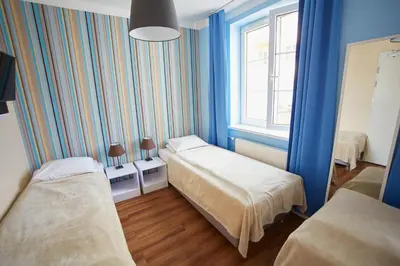 a blue room with two beds and a window at Premium Hostel in Kraków
