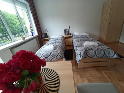 a room with two beds and a table with a vase of roses at DOM POD SOKOLICĄ in Będkowice