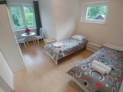 a bedroom with two beds and a table and two windows at DOM POD SOKOLICĄ in Będkowice