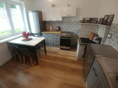 a kitchen with a table and a small kitchen with white cabinets at DOM POD SOKOLICĄ in Będkowice