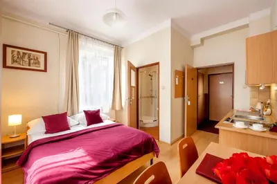 a bedroom with a large bed and a kitchen at Mały Kraków Aparthotel in Kraków