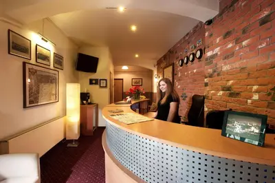 a woman sitting at a bar in a restaurant at Mały Kraków Aparthotel in Kraków