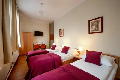 three beds in a hotel room with purple sheets at Mały Kraków Aparthotel in Kraków