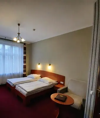 a bedroom with two beds and a couch and a table at Hotel Kazimierz II in Kraków