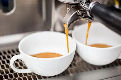 a coffee machine pouring coffee into two white cups at Abella Suites & Apartments by Artery Hotels in Kraków