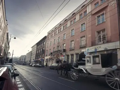 a horse drawn carriage on a city street with buildings at Abella Suites & Apartments by Artery Hotels in Kraków