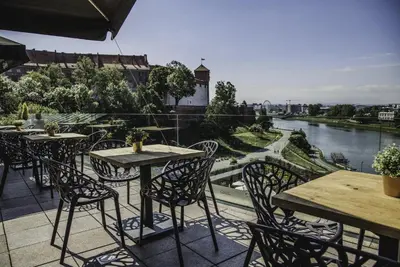a patio with tables and chairs and a view of a river at Hotel Pod Wawelem in Kraków