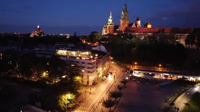 a view of a city at night with a castle at Hotel Pod Wawelem in Kraków