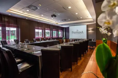 a conference room with tables and chairs and a screen at Farmona Hotel Business & SPA in Kraków