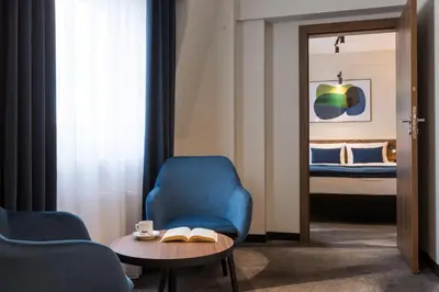 a room with a blue chair and a table and a bed at Ascot Premium Hotel in Kraków