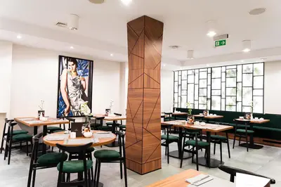 a restaurant with wooden tables and green chairs at Ascot Premium Hotel in Kraków