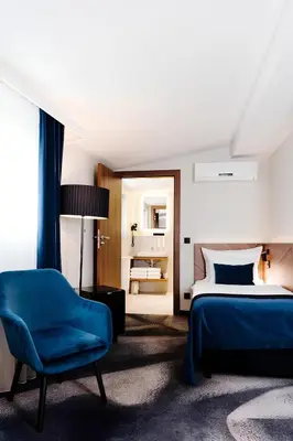 a bedroom with a bed and a blue chair at Ascot Premium Hotel in Kraków
