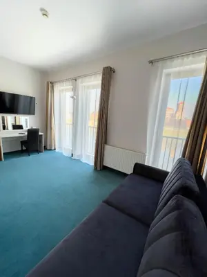 a living room with a couch and two windows at Hotel Poleski in Kraków