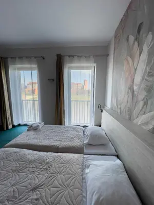 two beds in a bedroom with two large windows at Hotel Poleski in Kraków