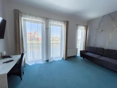 a living room with a couch and two large windows at Hotel Poleski in Kraków