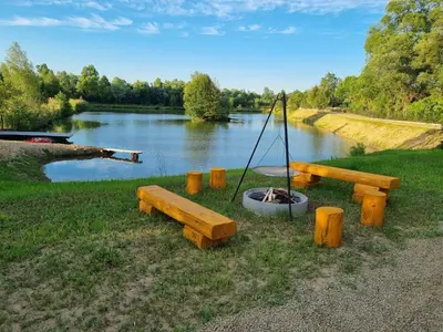 a group of wooden benches next to a lake at Wy_spa_Podolany in Gdów