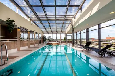 an indoor pool with a glass ceiling and chairs in a building at Qubus Hotel Kraków in Kraków