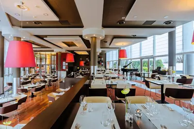 a restaurant with white tables and chairs and windows at Qubus Hotel Kraków in Kraków