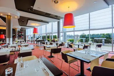 a restaurant with tables and chairs and windows at Qubus Hotel Kraków in Kraków