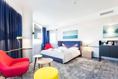 a hotel room with a bed and a red chair at Qubus Hotel Kraków in Kraków