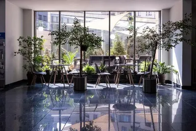 a room with tables and chairs and plants in a building at Laurel White Apartment with Jacuzzi Bath and Pool Access in Kraków