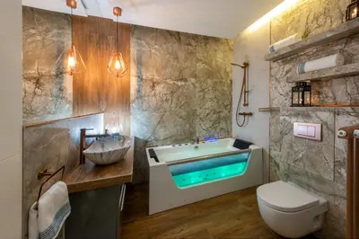 a bathroom with a tub and a toilet and a sink at Laurel White Apartment with Jacuzzi Bath and Pool Access in Kraków