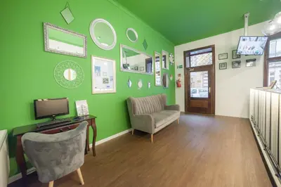 a living room with green walls and a chair and a television at Dizzy Daisy Hostel in Kraków