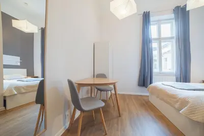a room with two beds and a table and chairs at Dizzy Daisy Hostel in Kraków