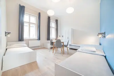 a room with three beds and a table in it at Dizzy Daisy Hostel in Kraków
