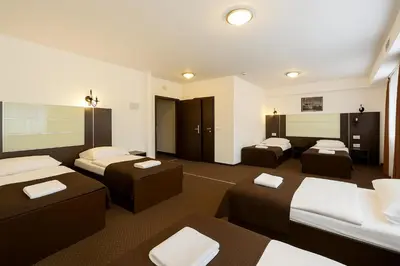 a hotel room with three beds and a room with two beds at Hotel Junior 2 in Kraków