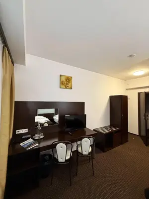 a room with a desk with chairs and a bed at Hotel Junior 2 in Kraków