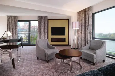 a living room with a desk and chairs and a television at Sheraton Grand Krakow in Kraków